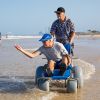 Man in Sandcruiser wheelchair in water on beach